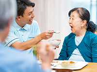 おばあさんの食事を補助する介護職の求人イメージ