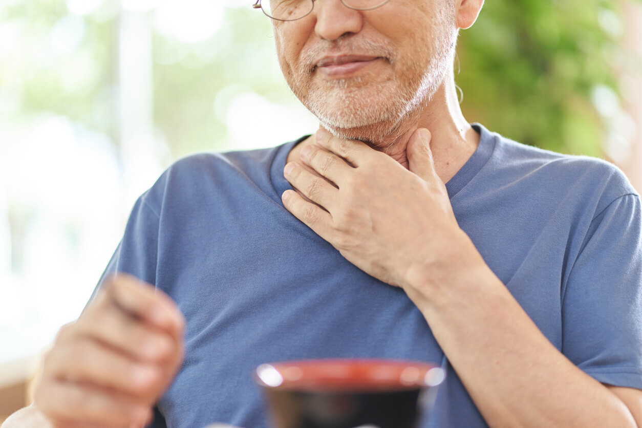 喉を押さえる男性