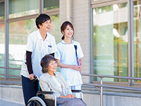 車椅子を押しながら会話をする介護職の求人イメージ