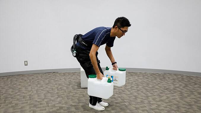 「HAL®︎腰タイプ介護支援用」を使い、合計24kgの給水容器を持ち上げる様子。